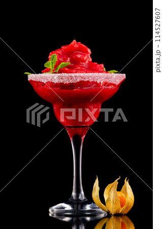 Closeup glass of red daiquiri strawberry cocktail decorated with mint and physalis isolated at black background. Closeup glass of red daiquiri strawberry cocktail decorated with mint and physalis isolated at black background. 114527607