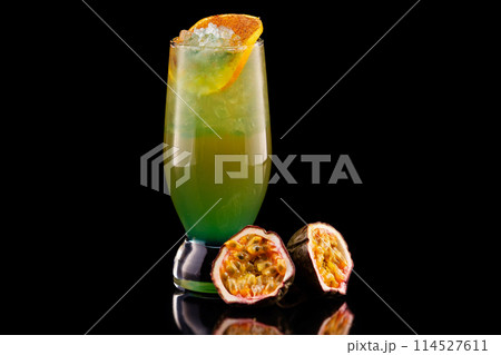 Glass of tropical cocktail with passion fruit, mango and pineapple isolated at black background. Glass of tropical cocktail with passion fruit, mango and pineapple isolated at black background. 114527611