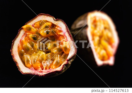 Macro image of two halves of passion fruit isolated at black background. Macro image of two halves of passion fruit isolated at black background. 114527613