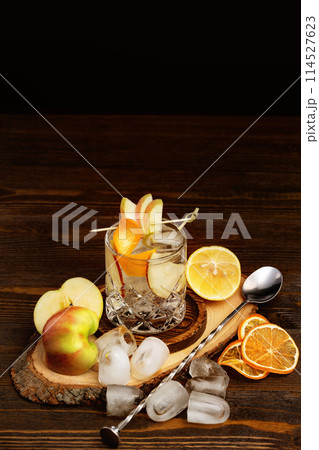 Vertical image of glass with whisky and apple juice cocktail at wooden table background. 114527623