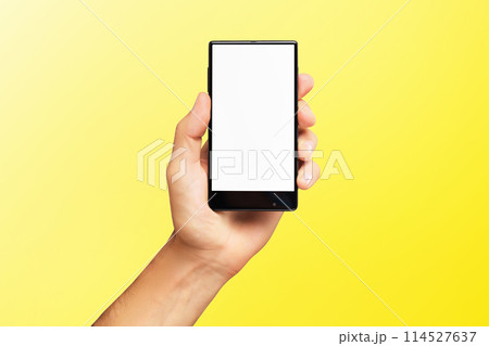 Mockup of male hand holding black frameless cell phone with blank screen isolated at yellow background. Mockup of male hand holding black frameless cell phone with blank screen isolated at yellow background. 114527637