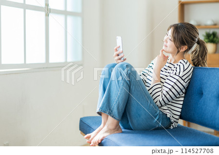 リビングでスマホを操作する若い女性。 リビングでスマホを操作する若い女性。 114527708
