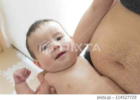産後の妊娠線が残る女性のお腹と笑顔で抱っこされるハーフの男の子の赤ちゃん 産後の妊娠線が残る女性のお腹と笑顔で抱っこされるハーフの男の子の赤ちゃん 114527729