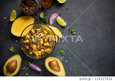 Cooking traditional tuna and mango tartare - chopped and mixed tuna, mango, cilantro and onion in a glass bowl Cooking traditional tuna and mango tartare - chopped and mixed tuna, mango, cilantro and onion in a glass bowl 114527818
