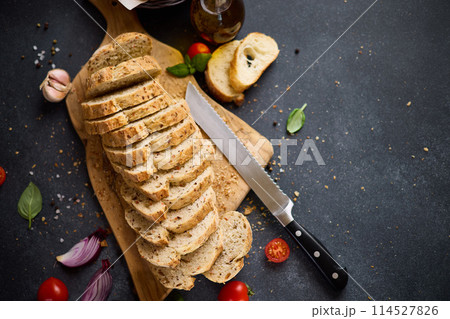sliced bread on wooden cutting board on dark table 114527826
