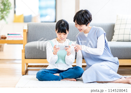 リビングでスマホを一緒に使う親子。 114528041
