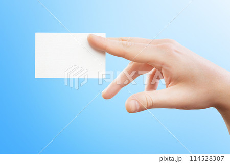 Male hand holding white business card at isolated blue background mockup. Male hand holding white business card at isolated blue background mockup. 114528307