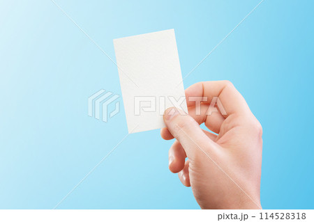 Male hand holding white business card at isolated blue background mockup. Male hand holding white business card at isolated blue background mockup. 114528318