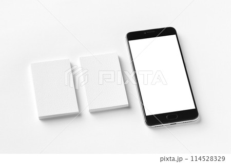 Mockup of two blank vertical business cards and cell-phone isolated at white textured paper. Mockup of two blank vertical business cards and cell-phone isolated at white textured paper. 114528329