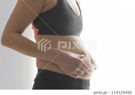 産後の妊娠線が残るお腹の肉をつまむ女性 産後の妊娠線が残るお腹の肉をつまむ女性 114529488