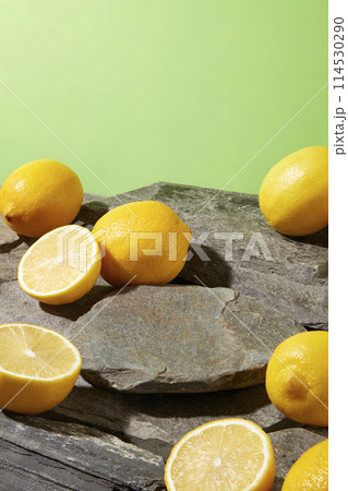 High angle shot a the rock platform with many fresh lemon and lemon pieces scattered lay above, over pastel green background. Empty rock pedestal for showing product which has lemon origin High angle shot a the rock platform with many fresh lemon and lemon pieces scattered lay above, over pastel green background. Empty rock pedestal for showing product which has lemon origin 114530290