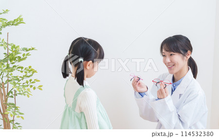 眼科医と眼鏡を選ぶ弱視の子供 114532380