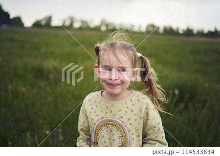 a beautiful blond girl with her toy bunny is playing in the field 114533634
