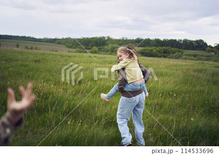 a mother rolls her daughters on her back, playing horse, kisses and hugs 114533696