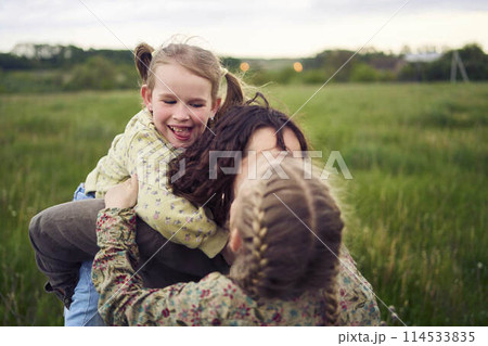 a mother rolls her daughters on her back, playing horse, kisses and hugs 114533835