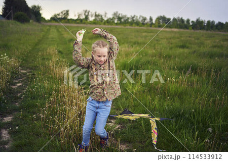 8-year-old girl flies a kite in a field in a thunderstorm 114533912