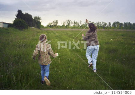 two little sisters and mother run and launch a kite in a field two little sisters and mother run and launch a kite in a field 114534009