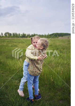 two sisters hug and kiss in the  field 114534029