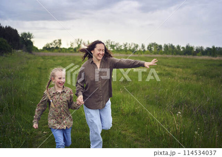 mother and children run holding hands in the field mother and children run holding hands in the field 114534037