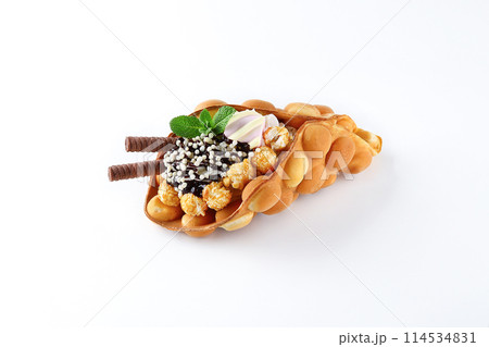 Hong kong or bubble waffle with ice cream, fruits, chocolate sauce and colorful candy isolated on white background Hong kong or bubble waffle with ice cream, fruits, chocolate sauce and colorful candy isolated on white background 114534831