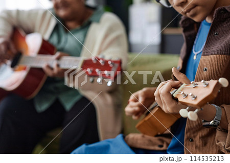 Close up of unrecognizable African American girl playing ukulele during music class indoors copy space Close up of unrecognizable African American girl playing ukulele during music class indoors copy space 114535213