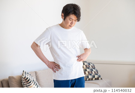 皮下脂肪をつまんで落ち込む男性 114540032