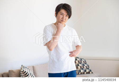 皮下脂肪をつまんで考え込む男性 114540034