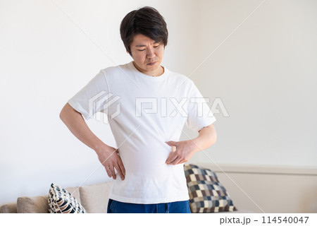 皮下脂肪をつまんで落ち込む男性 皮下脂肪をつまんで落ち込む男性 114540047