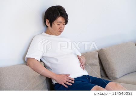食べ過ぎたお腹を見て落ち込む男性 食べ過ぎたお腹を見て落ち込む男性 114540052