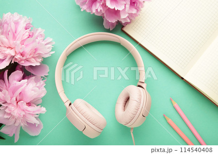 Modern pink headphones with flowers peonies and notebook on mint background Modern pink headphones with flowers peonies and notebook on mint background 114540408