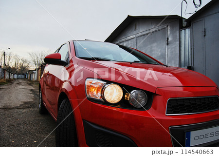 Beautiful red car.Foreground of a red car with headlights on. 114540663