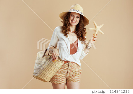 smiling elegant woman in blouse and shorts against beige smiling elegant woman in blouse and shorts against beige 114541233
