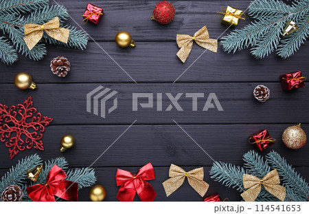 Christmas decoration. Fir-tree branch with balls, gifts and bows on a black background 114541653