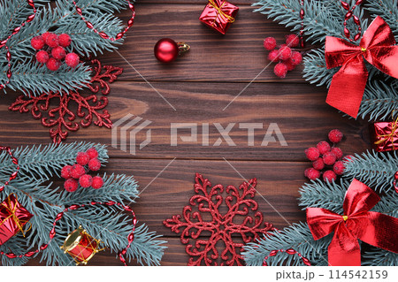 Christmas decoration. Fir-tree branch with balls, gifts and bows on a brown background 114542159