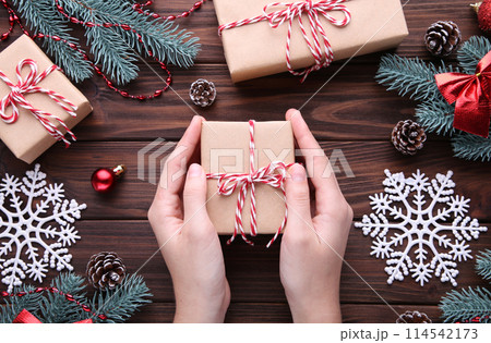 Female hands holding gift box on brown wooden table 114542173