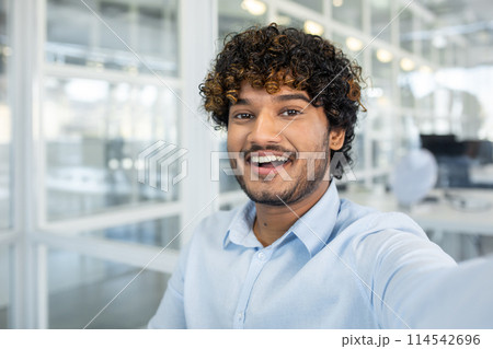 Cheerful young man snapping a selfie in a bright, modern office space, showcasing joy and a professional atmosphere. Cheerful young man snapping a selfie in a bright, modern office space, showcasing joy and a professional atmosphere. 114542696