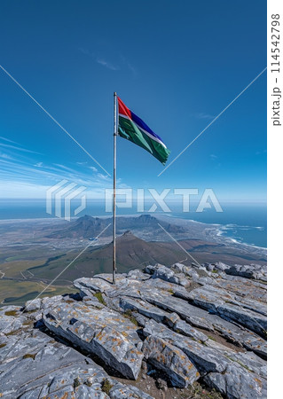 flag of Namibia flutters proudly atop a mountain, symbolizing unity, liberty, and diversity in the stunning natural setting. 114542798