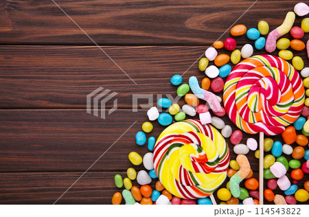 Colorful lollipops and different colored round candy on brown background Colorful lollipops and different colored round candy on brown background 114543822