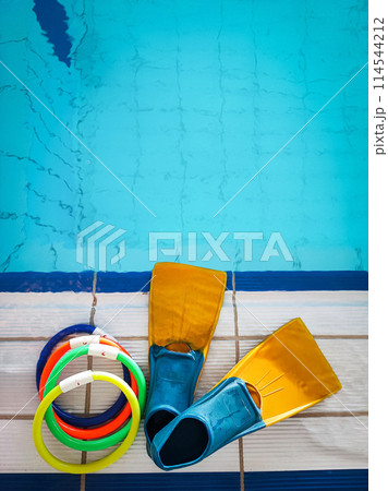Resistant equipment - fins, swimming goggles, rescue board on the side near the pool. Preparing athletes for the Olympic Games, swimming. Resistant equipment - fins, swimming goggles, rescue board on the side near the pool. Preparing athletes for the Olympic Games, swimming. 114544212