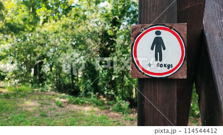 Restrictive sign with the image of a human symbol and a weight limit of 60 kg against the background of nature. 114544412