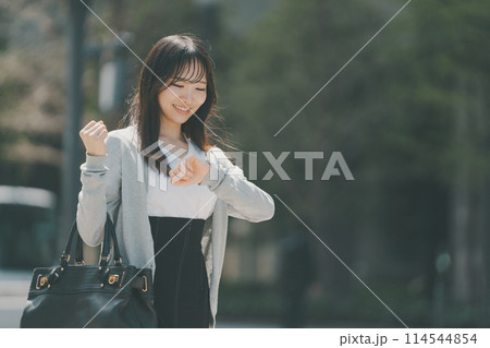 腕時計を見る通勤途中のOL 114544854