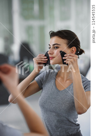 Facial skin care. A woman is doing a face massage using gouache stones. Facial skin care. A woman is doing a face massage using gouache stones. 114545535