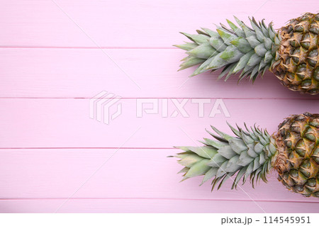Two ripe pineapples on a pink wooden background 114545951