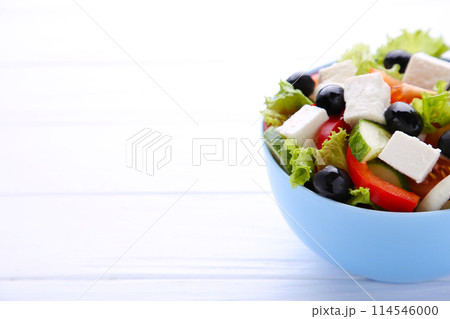 Fresh vegetable salad on bowl on white wooden background 114546000