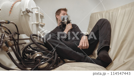 Military man receiving treatment in industrial hyperbaric chamber 114547443