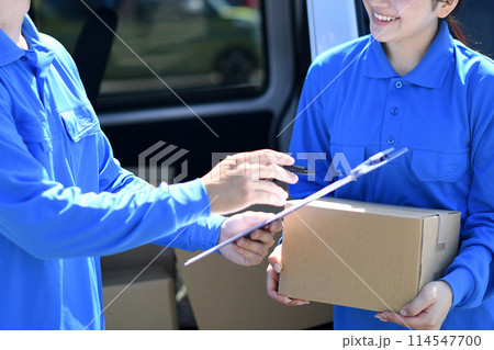 屋外で会話をするドライバーの作業員の男女 114547700