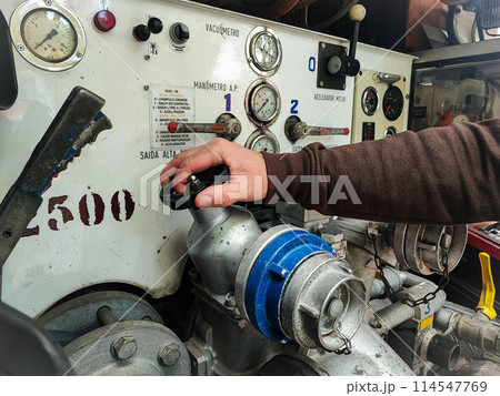 Close-up of a man's hand with fire equipment in a fire truck. Man turns control levers Close-up of a man's hand with fire equipment in a fire truck. Man turns control levers 114547769