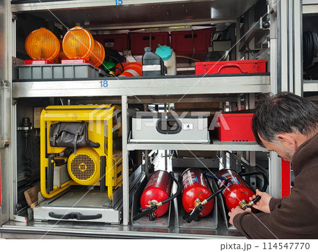 Close-up of a man's hand with fire equipment in a fire truck. Man turns control levers Close-up of a man's hand with fire equipment in a fire truck. Man turns control levers 114547770