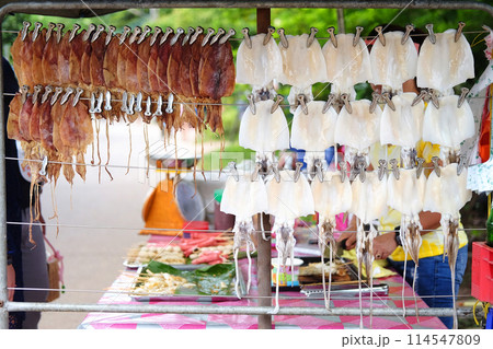 Grilled dried squids hanging on the rack show. Seafood on street food in Thailand 114547809