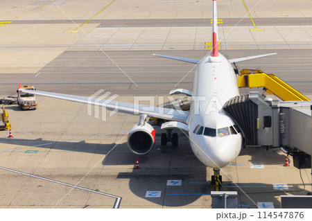 Airplane at gate with boarding passengers and ground crew 114547876